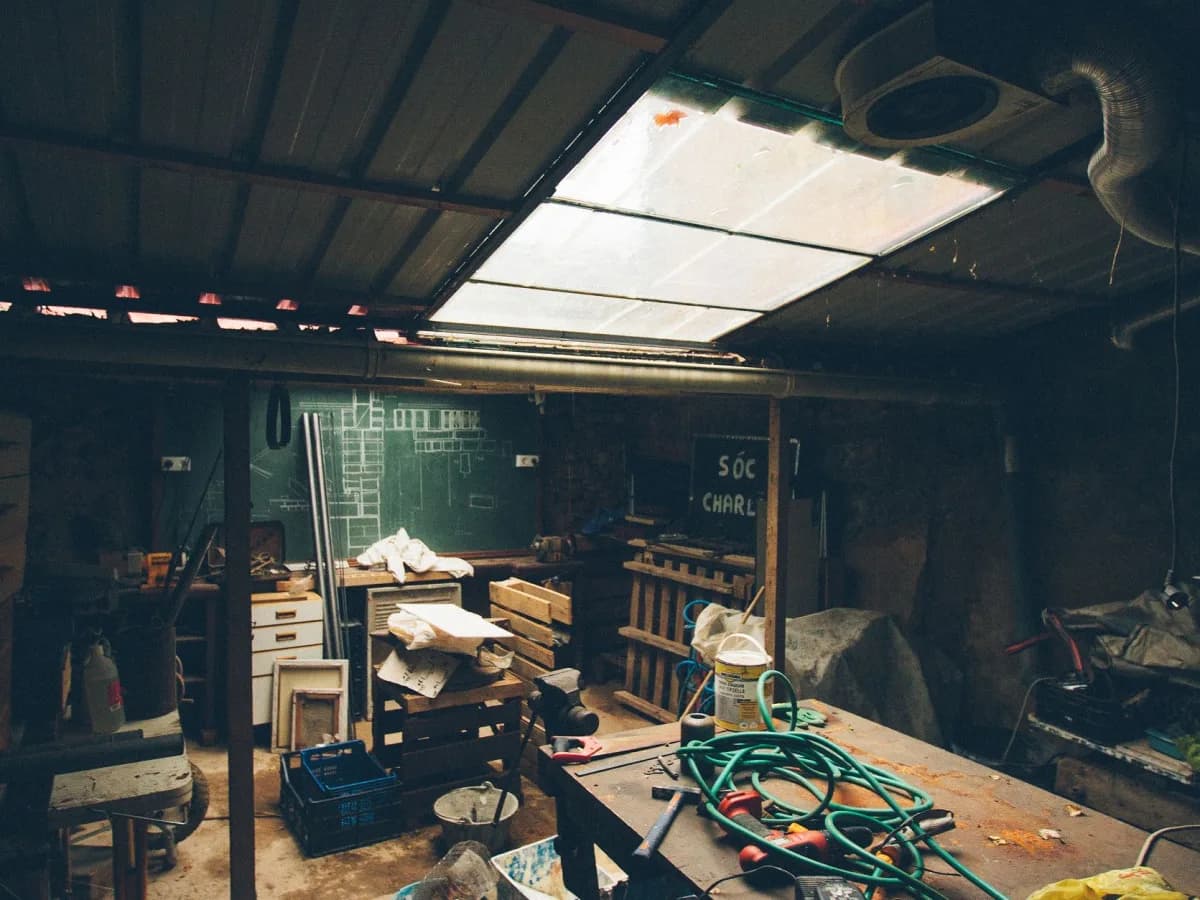 Cluttered basement storage area with boxes, chairs, and household items