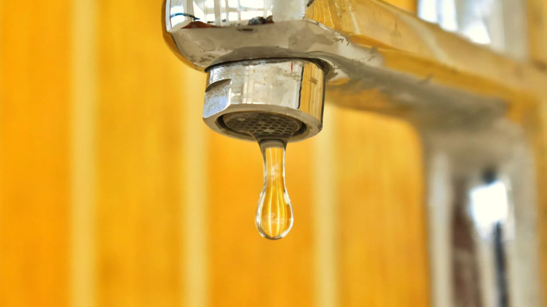 Homeowner fixing a leaking faucet under the sink