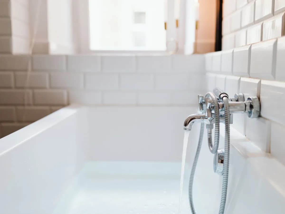 Homeowner applying caulk around bathtub