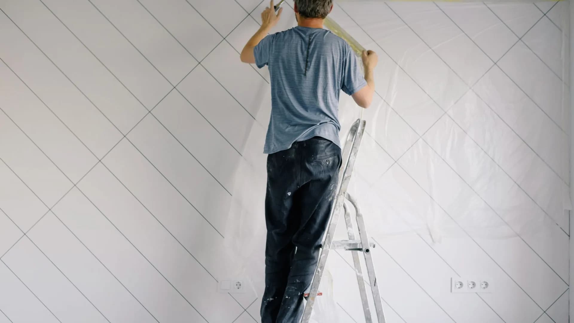 A homeowner repainting interior walls in a tidy living room.
