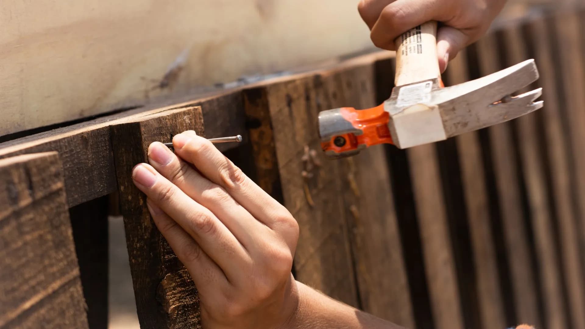 A person performing fence repair in a backyard