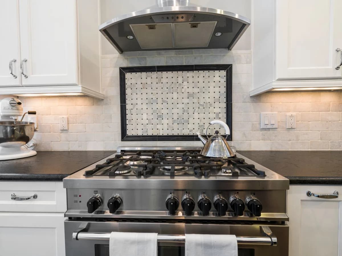 Close-up of a newly installed range hood over a gas stove in a kitchen
