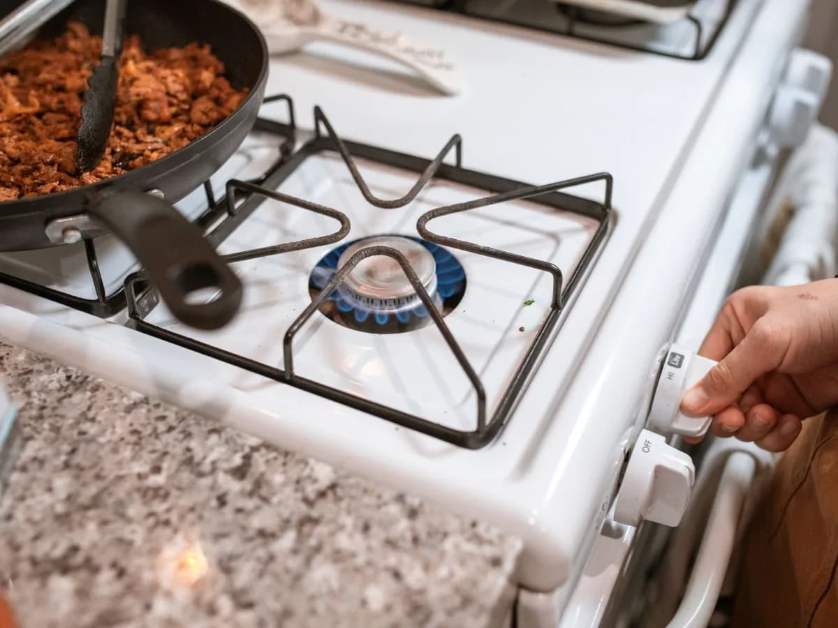 Technician disconnecting a gas line from a stove