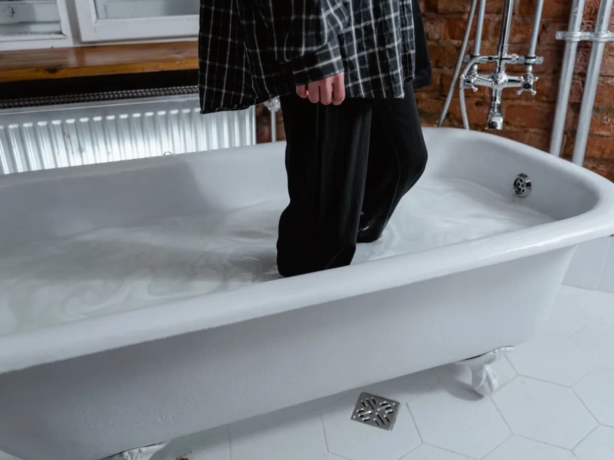 Homeowner checking caulking around bathtub for discoloration.
