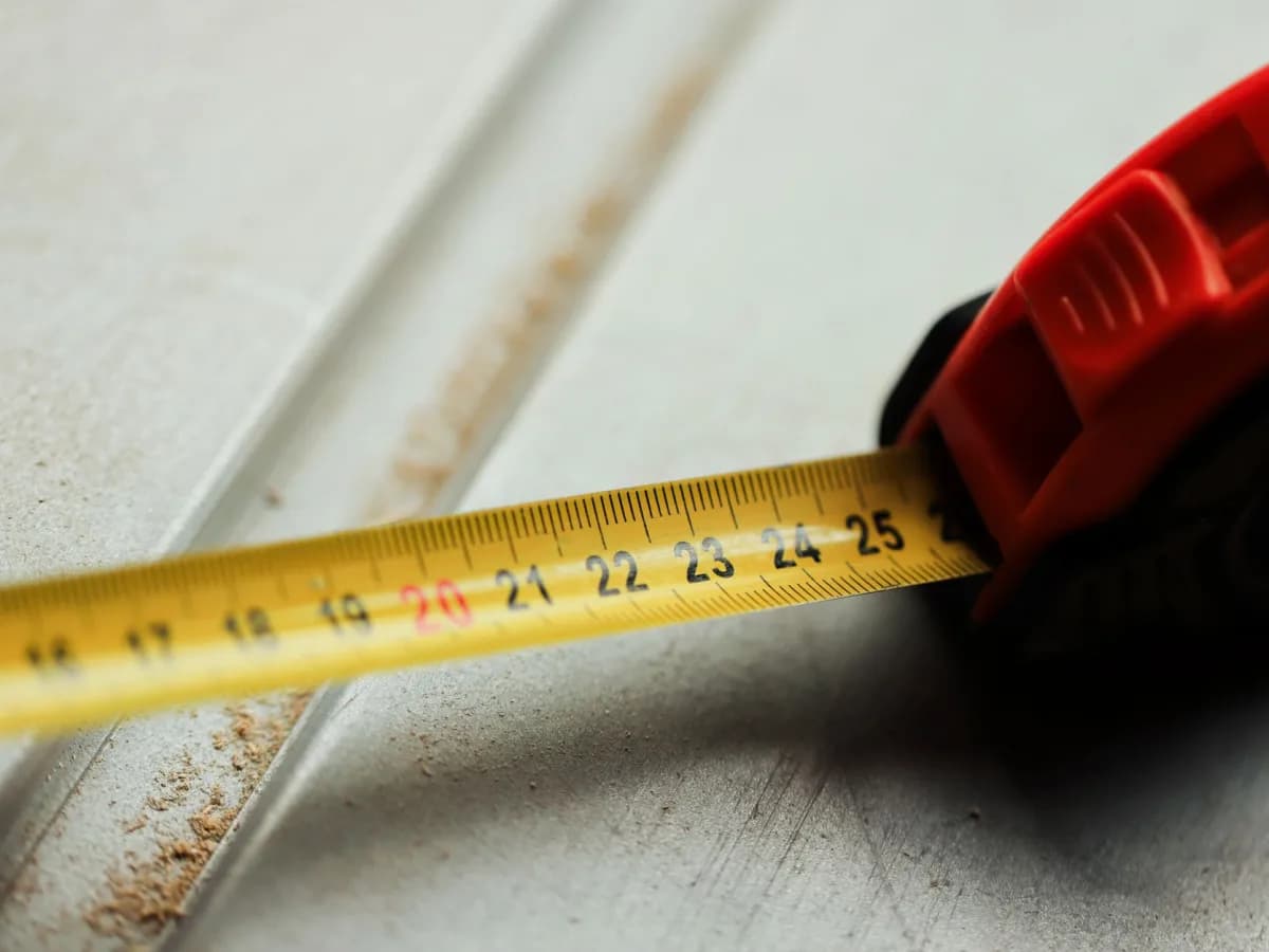 Measuring tape across a tiled kitchen backsplash above a countertop.