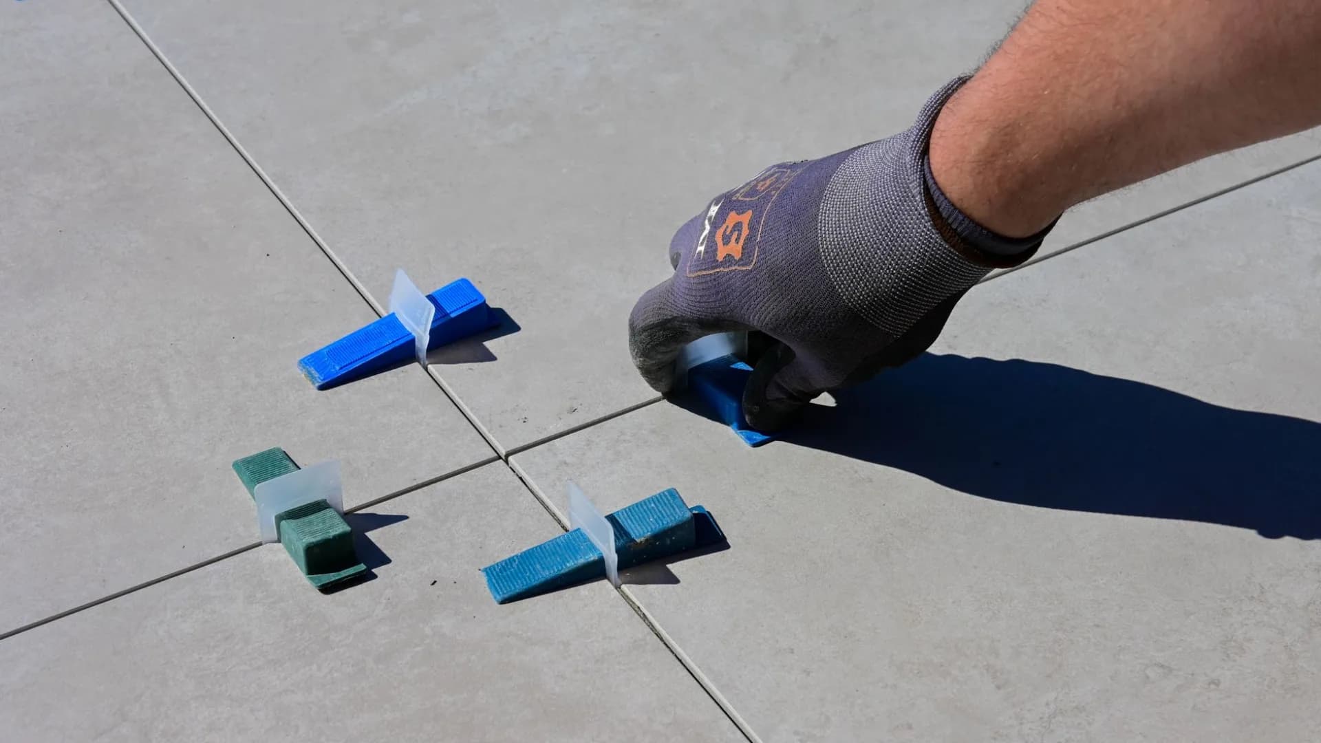 Installer aligning subway tile on a kitchen backsplash above a countertop.