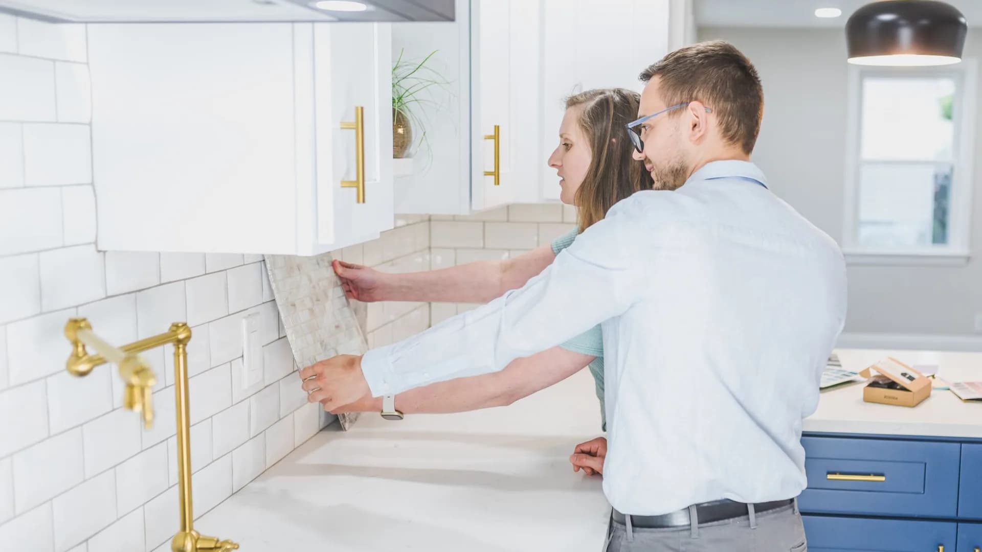 Installer setting ceramic tile on a kitchen backsplash above a protected countertop.