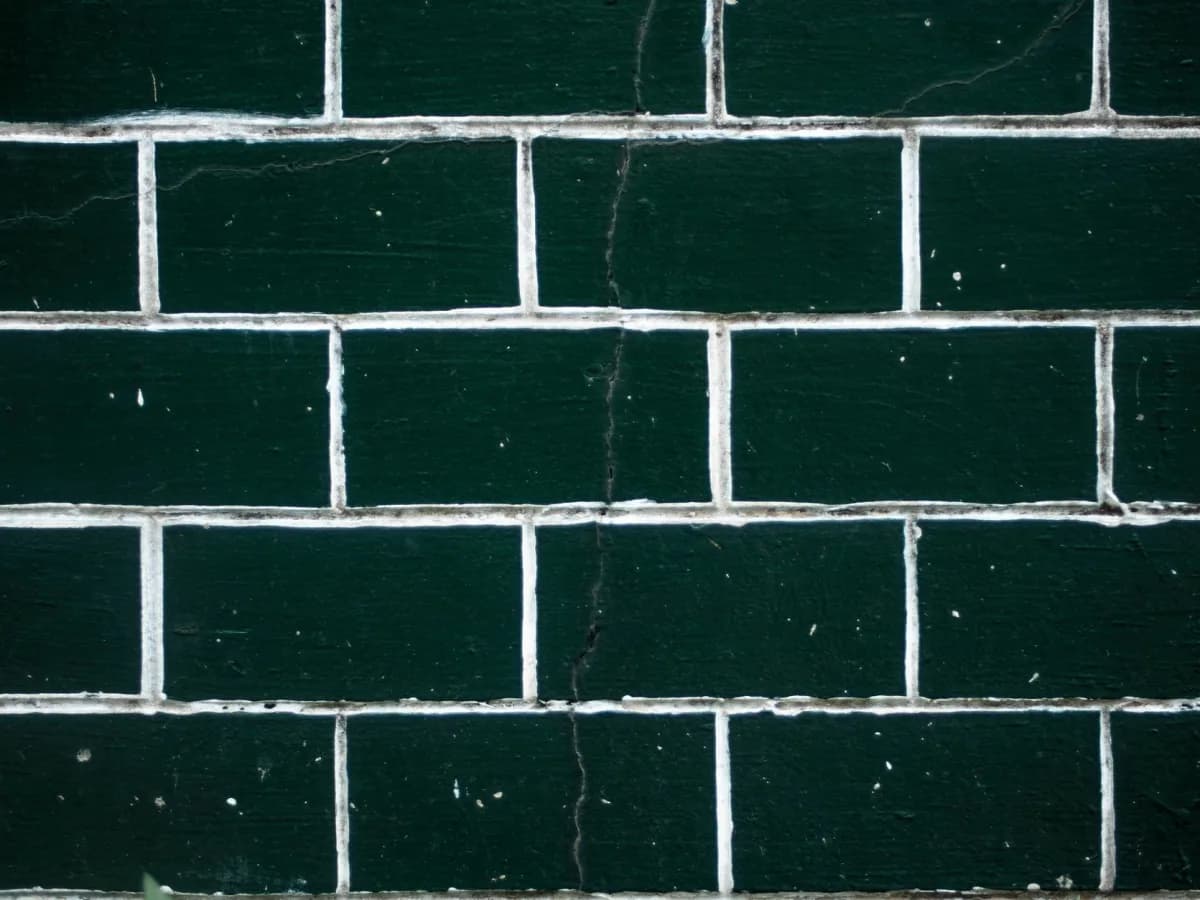 Close-up of cracked kitchen backsplash tile and worn grout near a countertop.