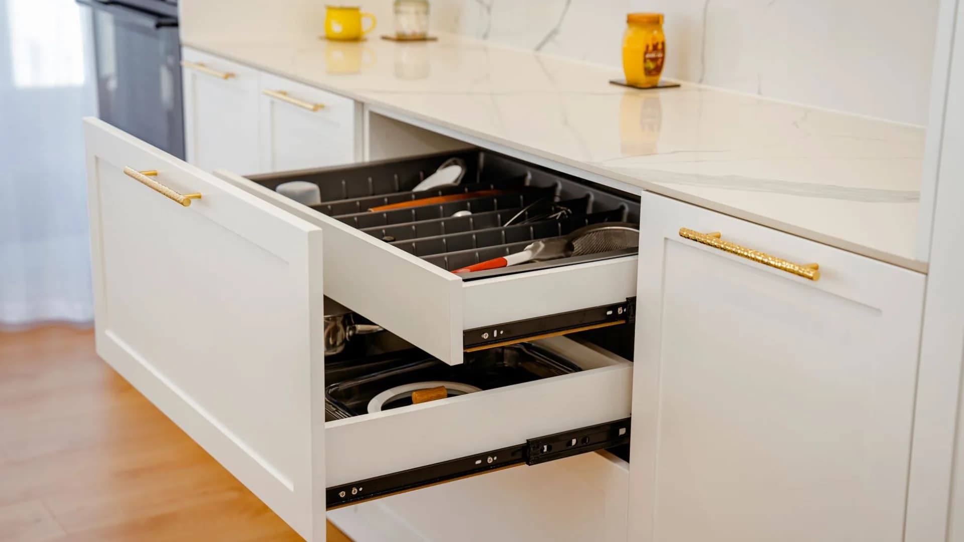 Technician repairing a drawer slide in a residential kitchen cabinet.