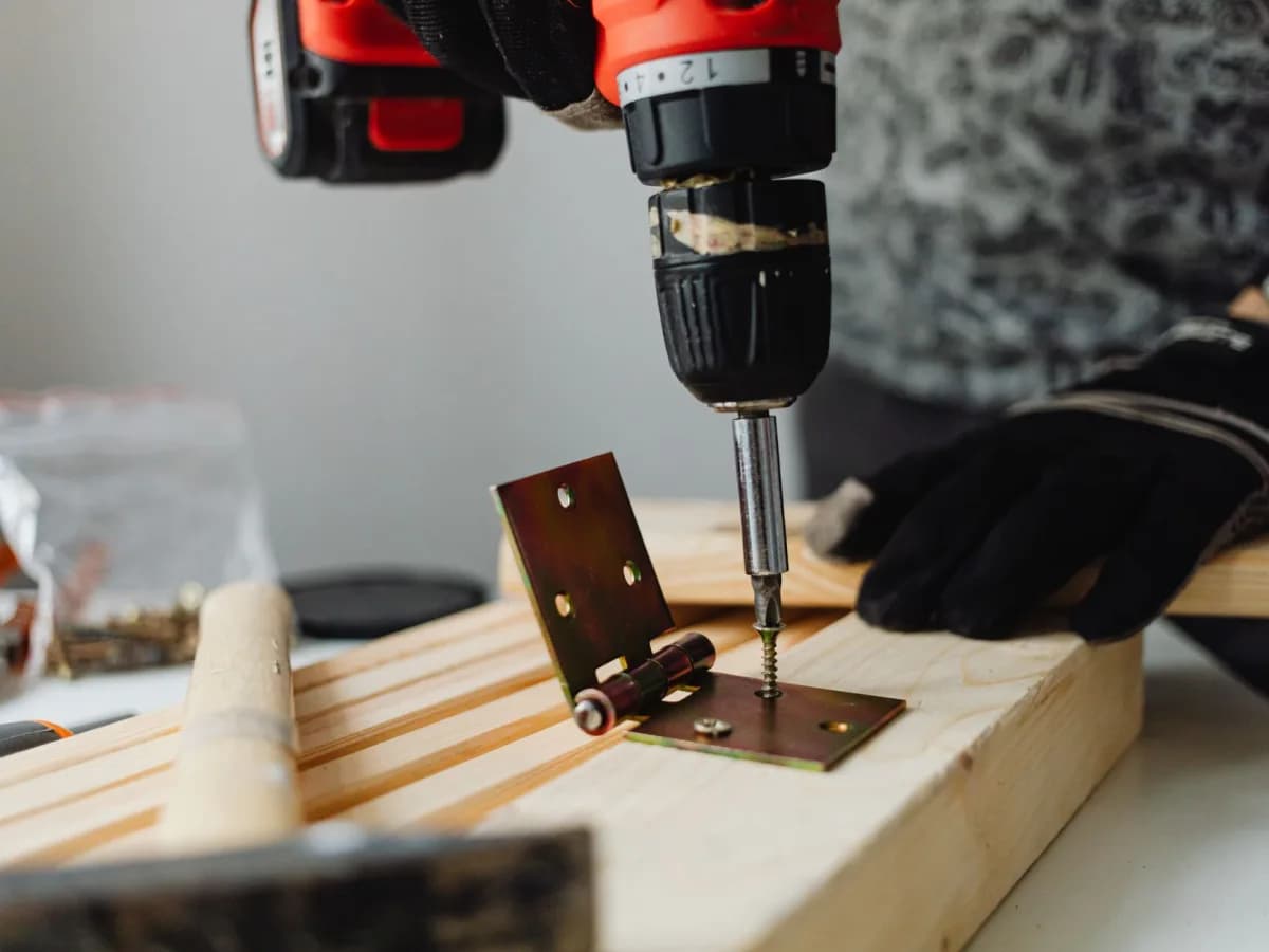 Close-up of a screwdriver adjusting a concealed kitchen cabinet hinge.