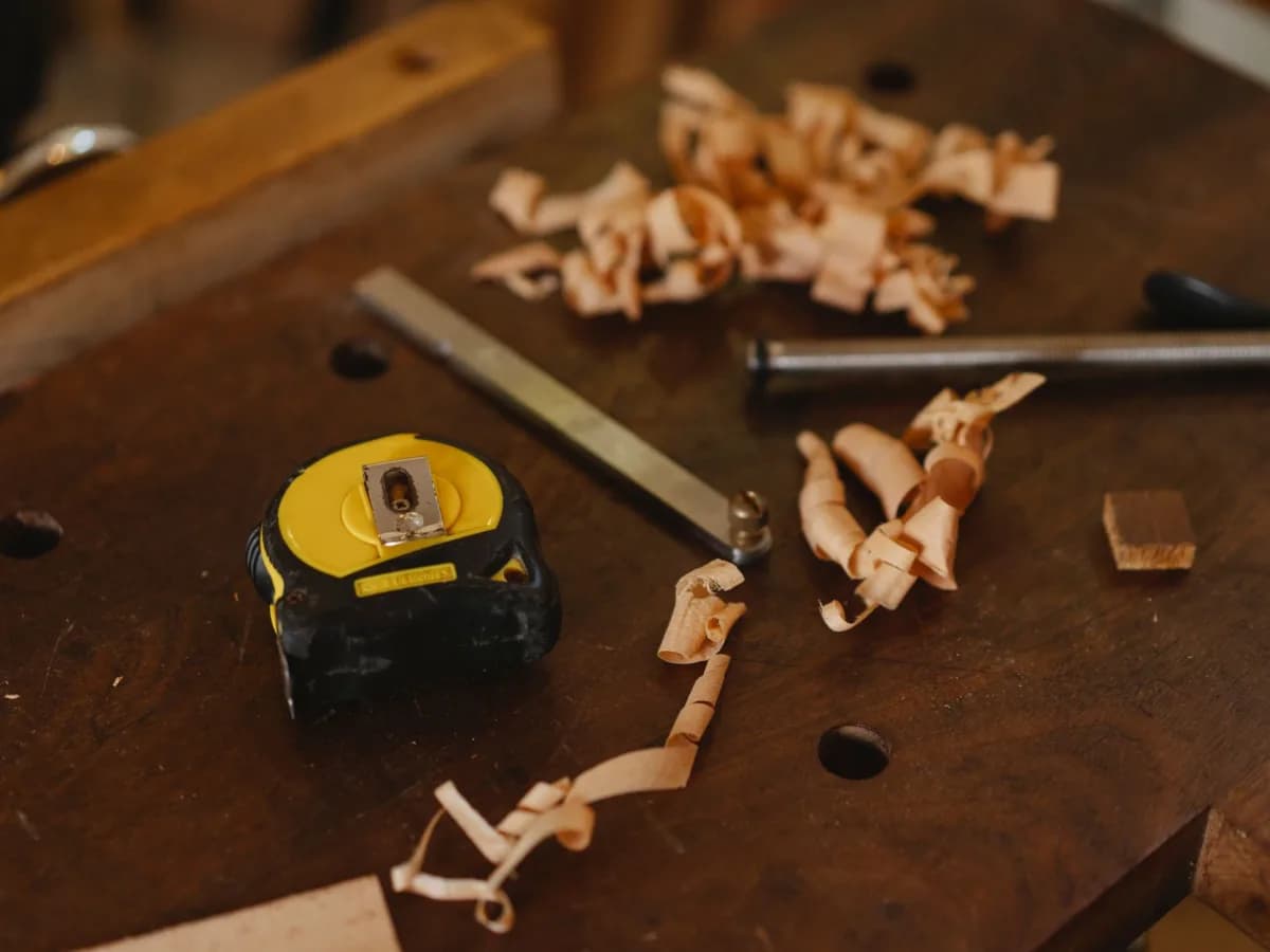 Tape measure checking the screw-hole spacing on a cabinet pull beside cabinet hardware.