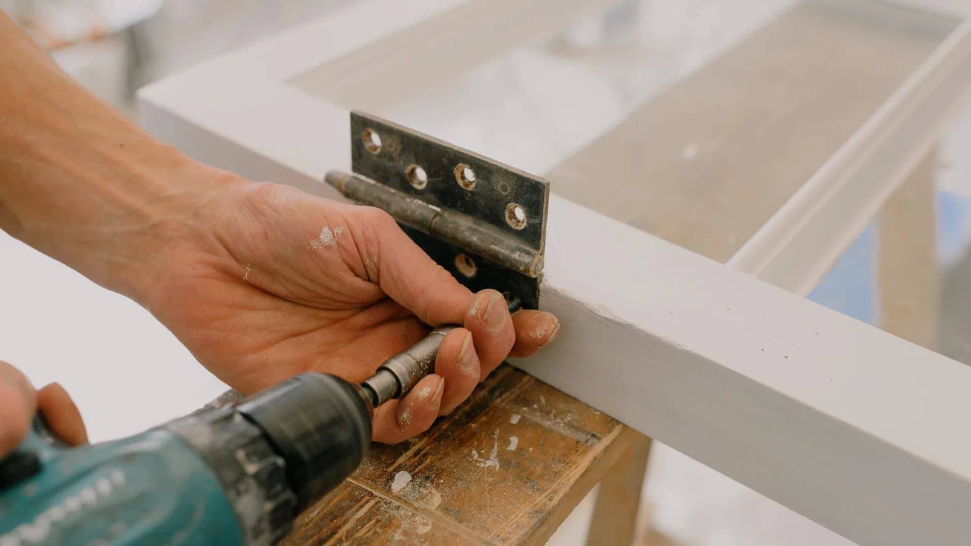 Worker adjusting a concealed hinge on a kitchen cabinet door