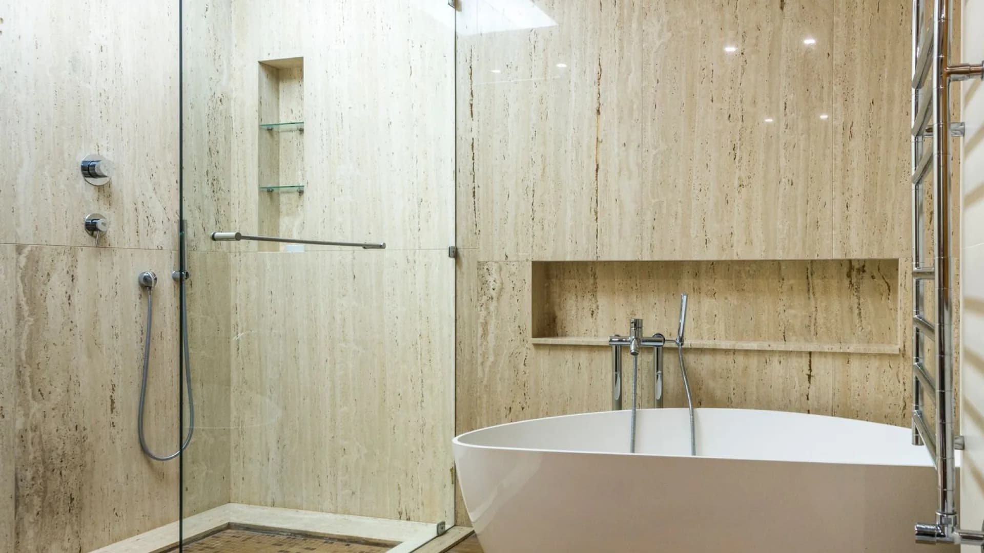 Worker installing porcelain tile in a residential shower during a bathroom renovation.
