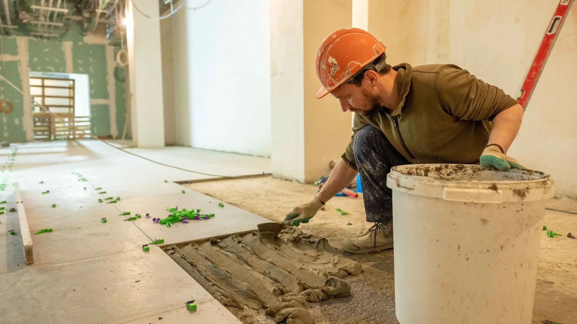 Tradesperson removing damaged floor tile during a residential bathroom renovation.