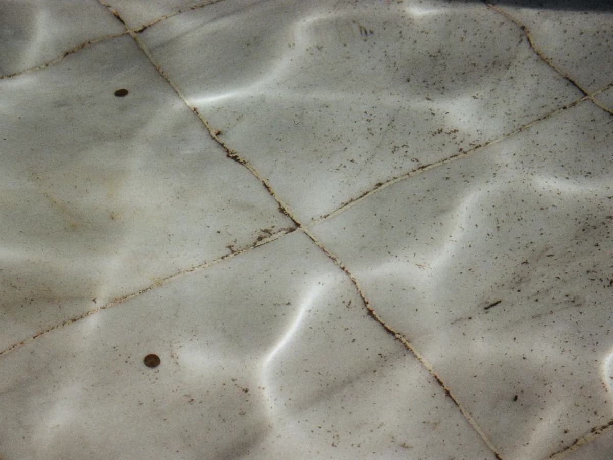 Cracked shower grout and loose tile near a bathtub surround.