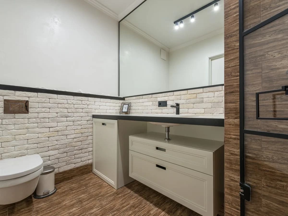 Open bathroom vanity cabinet showing plumbing connections and moisture staining.