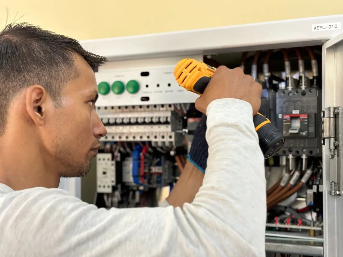 Electrician testing wiring at a bathroom electrical box during renovation