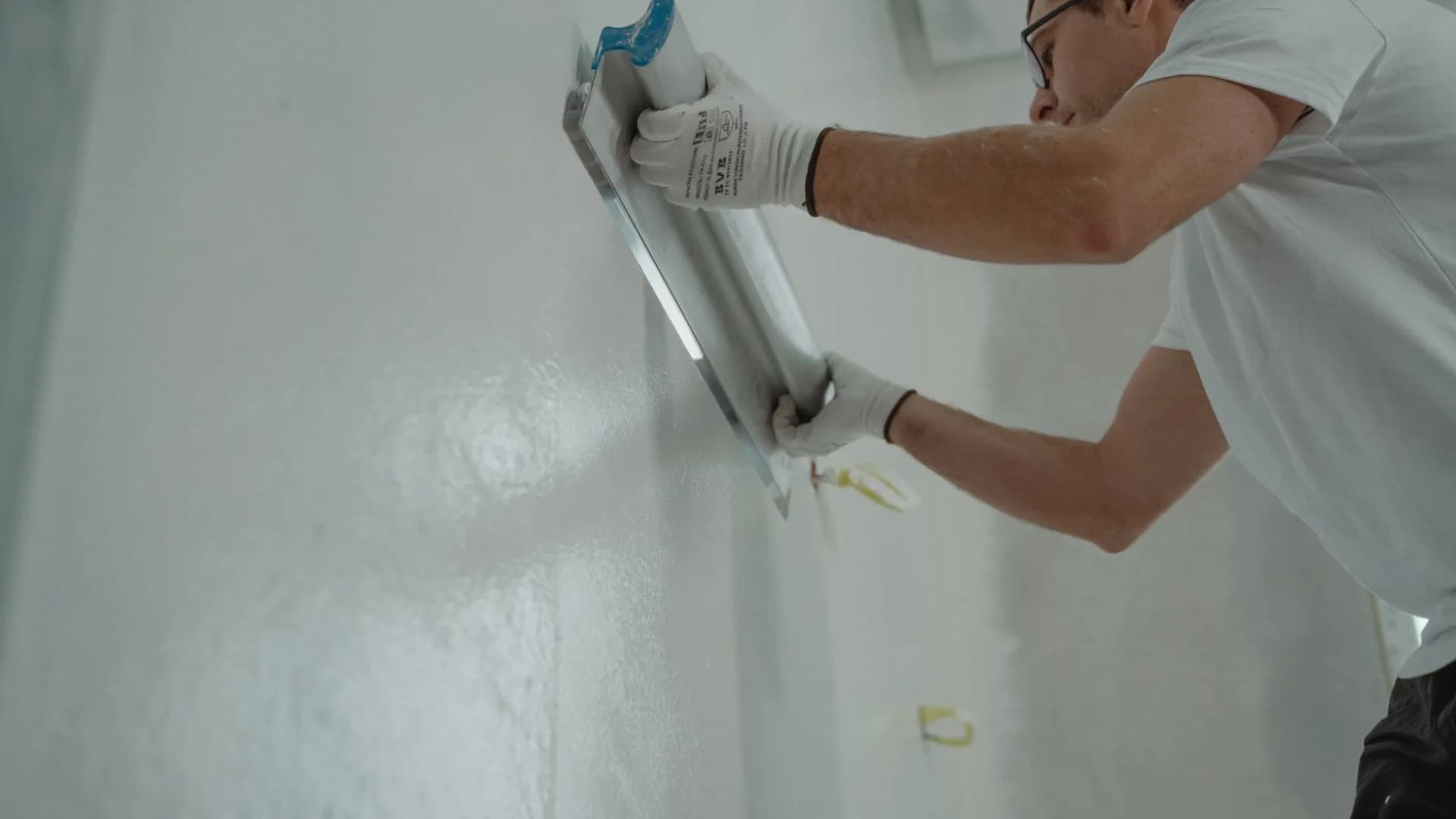Tradesperson applying waterproofing membrane to a shower wall during a bathroom renovation.